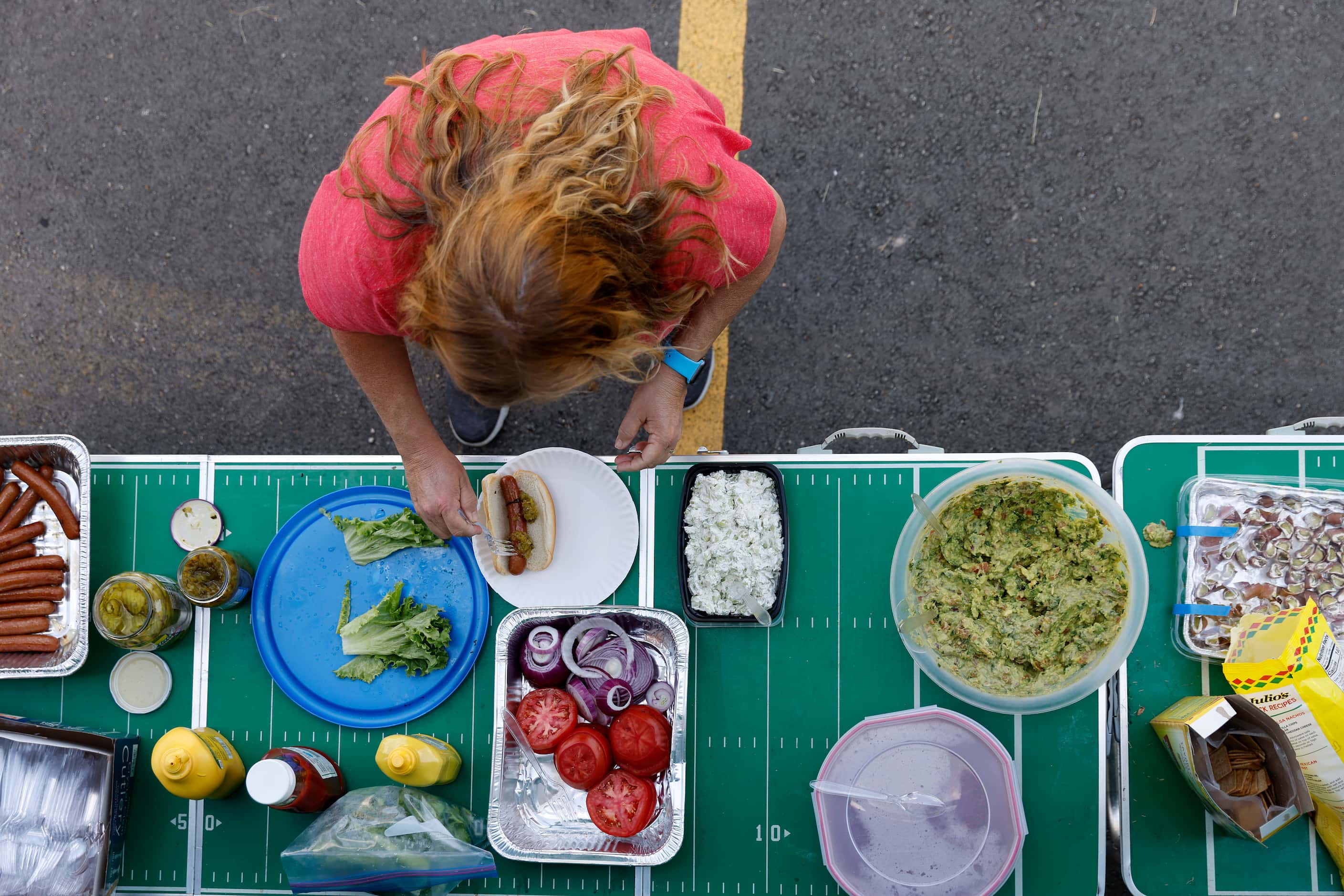 A Texas Rangers fan makes herself a lunch at an Opening Day tailgate party on private...
