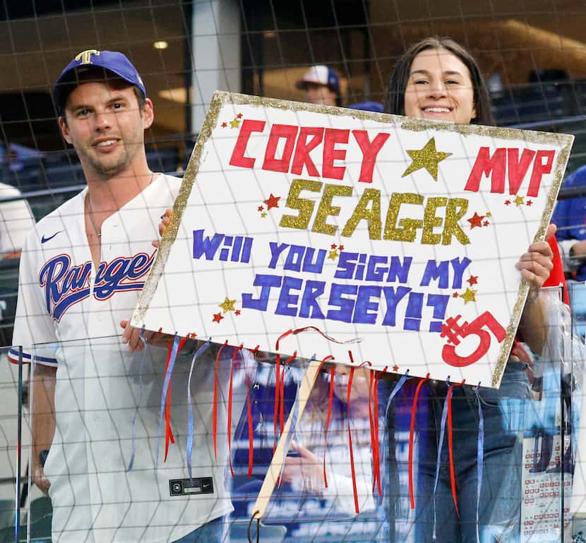 Texas Rangers fans Mickey Wilkins of Dallas and Amanda Berkowitz of Dallas hold a sign...