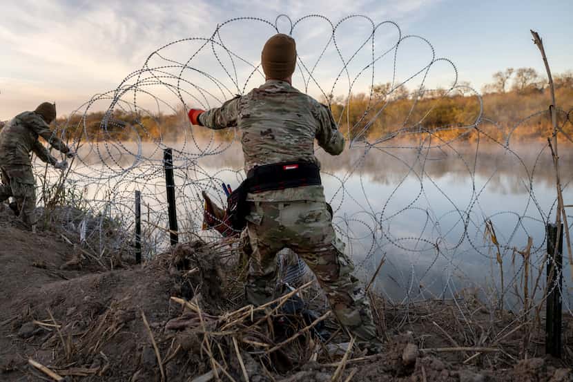 Texas National Guard soldiers install additional razor wire lie along the Rio Grande on...