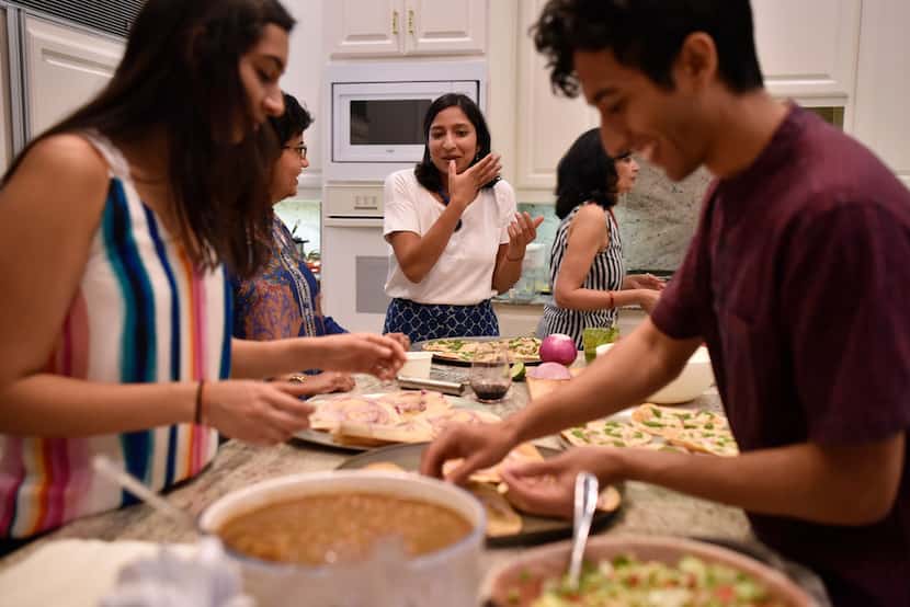 Food writer Priya Krishna, center, tastes a traditional Indian sauce while eating with...