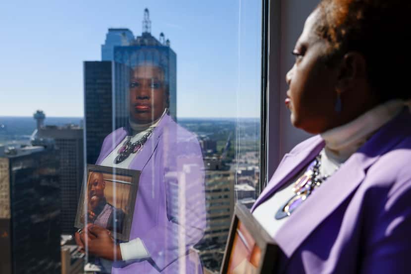 Dee Crane is reflected on a window against the Dallas skyline as she poses for a photo...