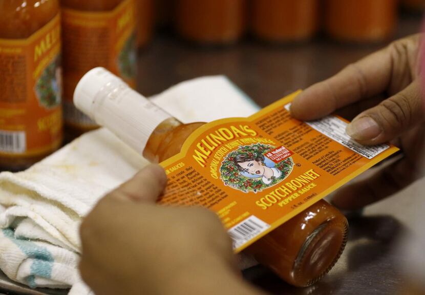 
A worker puts a Melinda’s Original Scotch Bonnet Pepper Sauce label on a bottle at the...