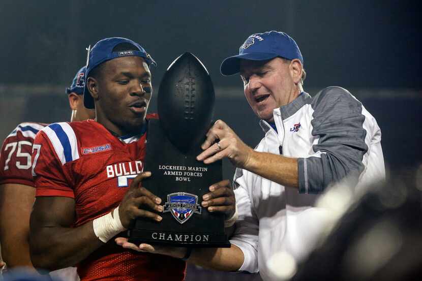 Louisiana Tech head coach Skip Holtz, right, passes the championship trophy to safety Xavier...
