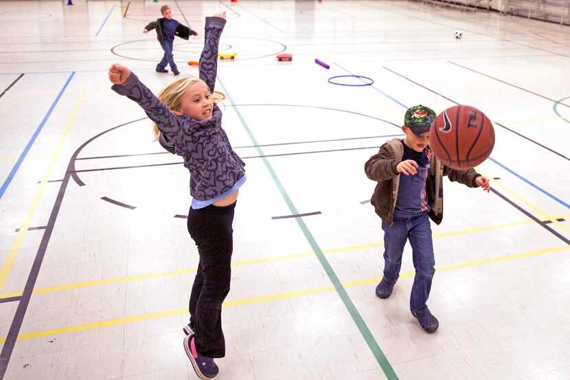 Payton Larson, 8,  celebrated after making a basket while playing with her brother Luke, 5,...