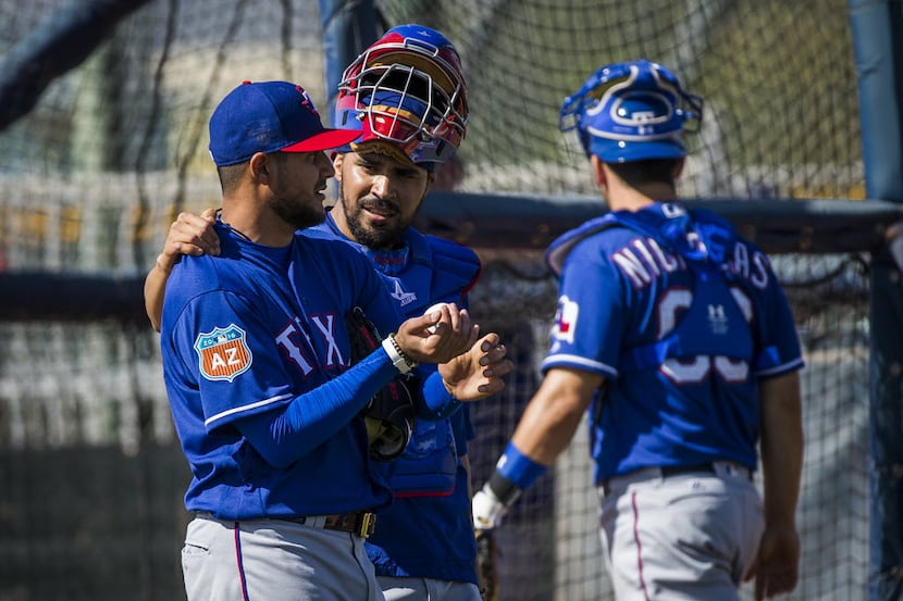Texas Rangers catcher Robinson Chirinos puts his arm around pitcher Martin Perez after he...