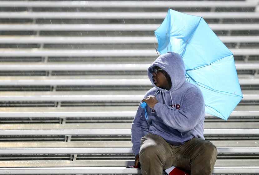 A fan on the Cedar Hill side looses control of his umbrella in a game against DeSoto during...