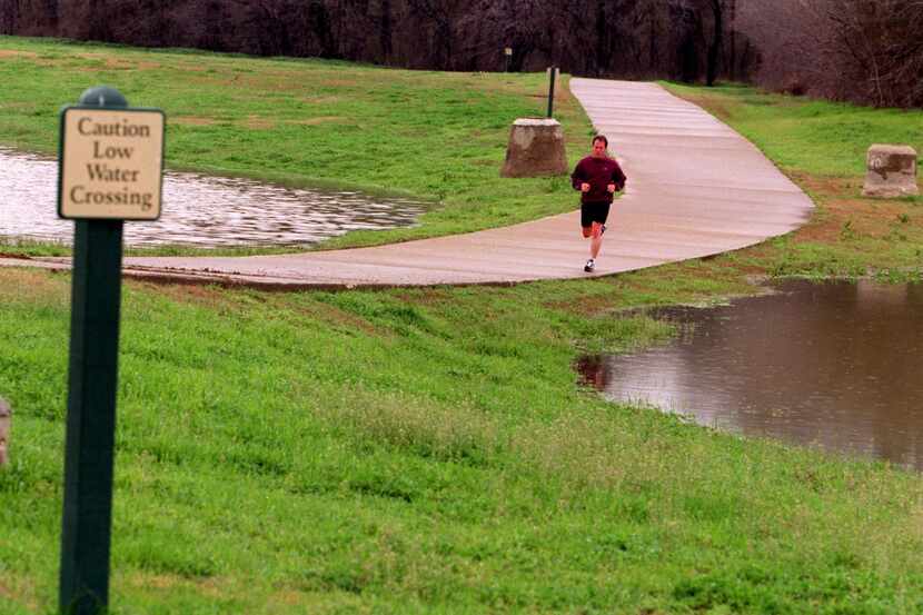 An unidentified jogger exercises along Campion Trail in north Irving. Flooding along the...