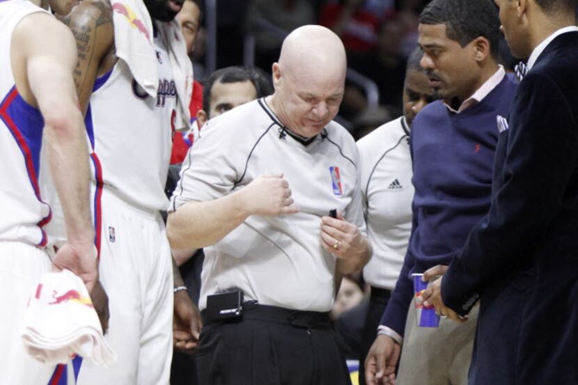 Referee Joe Crawford, center, walks off the court after an injury during the first half of...