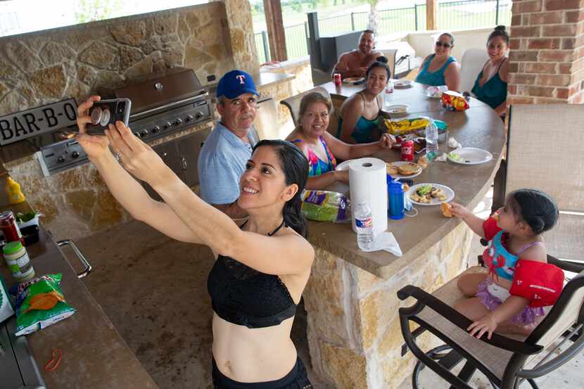 Imelda Mendoza takes a selfie with her family as they eat after swimming in a backyard pool...
