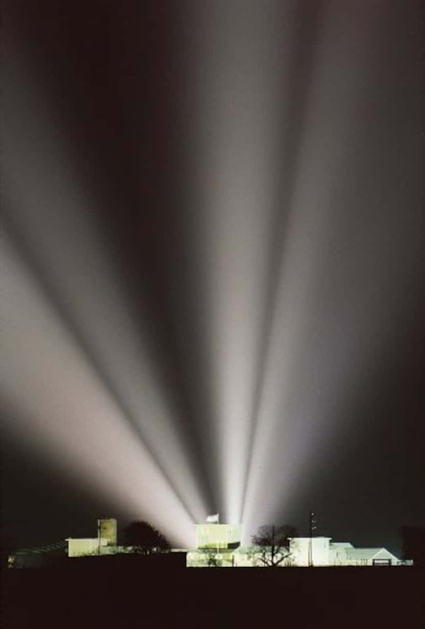 Floodlights slice through the night sky behind the Branch Davidian compound near Waco in...