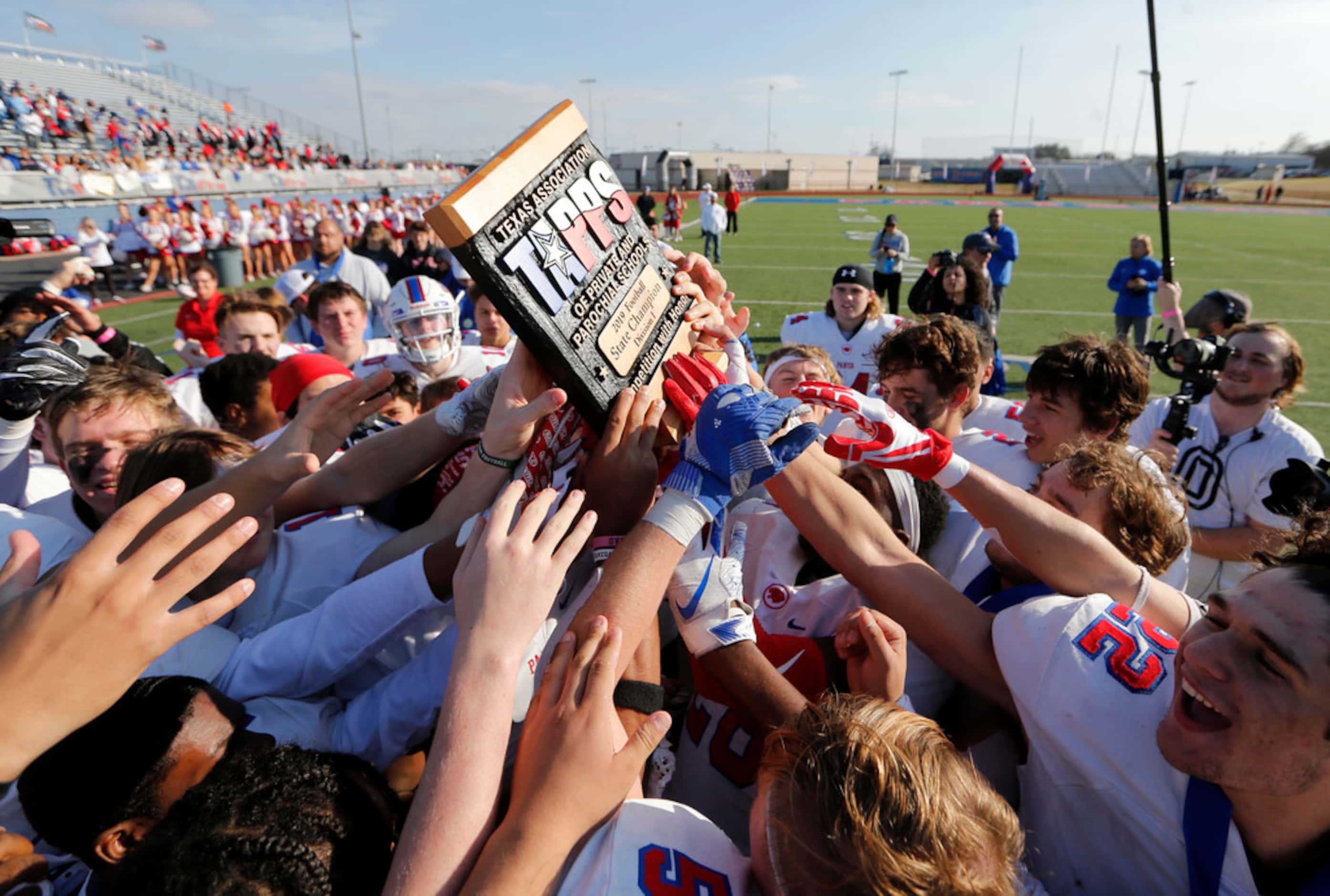 Parish Episcopal's football team hoists the trophy after receiving it during the awards...