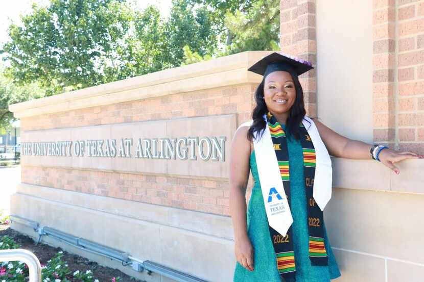 African American woman wearing a graduation cap and sash poses in front of the University of...