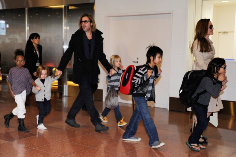 Stars on the move: Brad Pitt and Angelina Jolie escort their kids through Haneda Airport in...