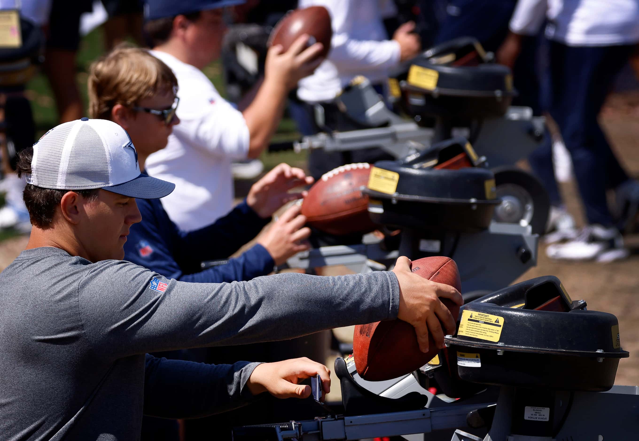Footballs are loaded into throwing machines at the end of a mock game workout in Oxnard,...