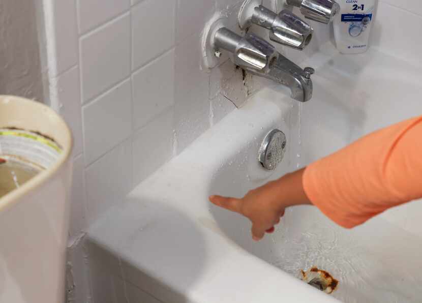 Water runs down the edge of the tub as Guadalupe Arista points out areas of her apartment...