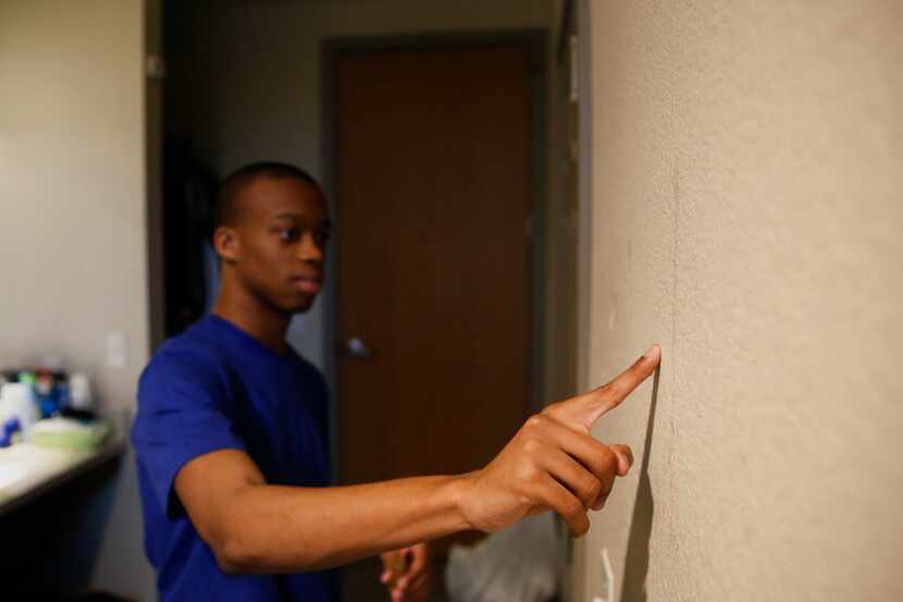 Using anointed oil, Jaylon Miller makes the sign of the cross on the wall of his dorm room...