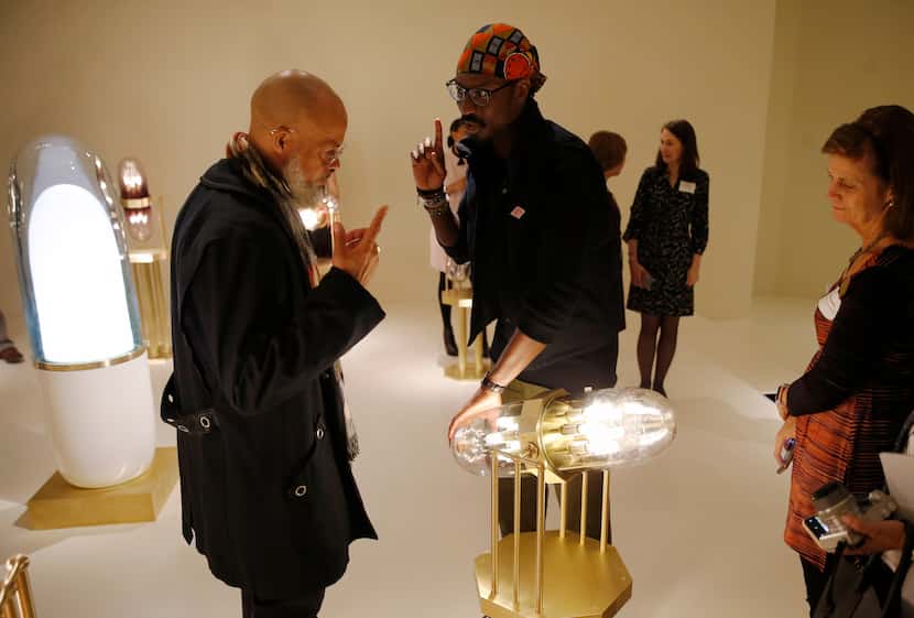 Artist Ini Archibong (center) explains how his piece called "theoracle" works to Jackson...