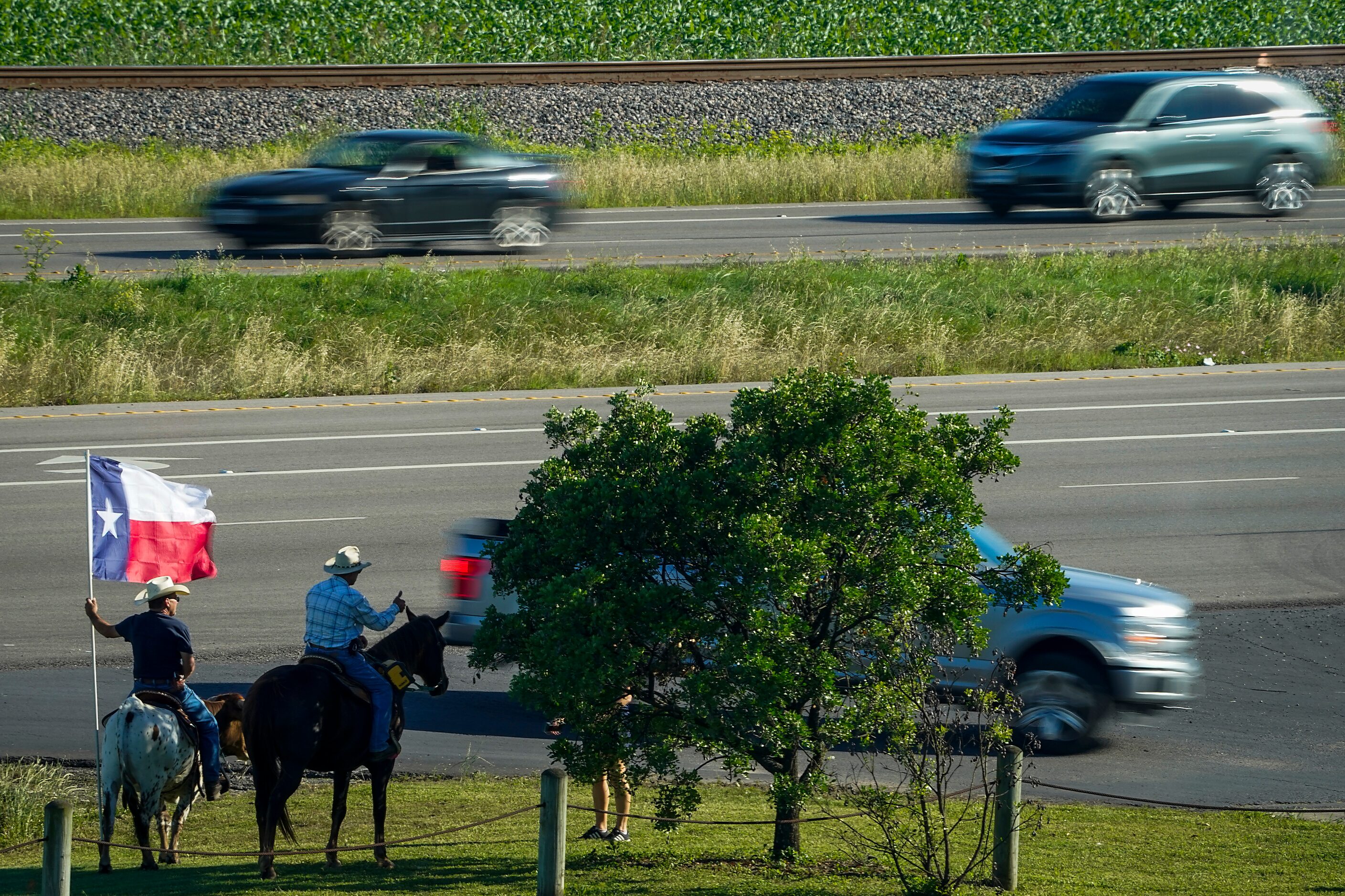 Men on horseback, and atop the back of a longhorn, greet fans turning into the praking lot...