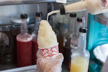 A shaved ice is being made with homemade syrup which includes organic sugars and natural...