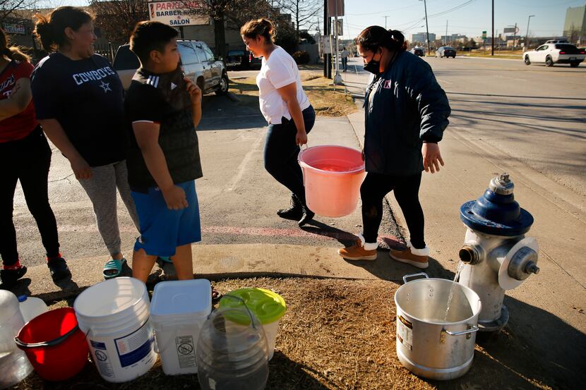 Residents Maria Mata, right, and her daughter, Dariela, carry a large bucket of water to...