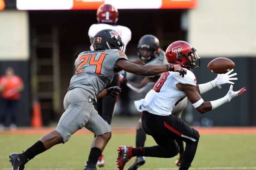 Texas Tech wide receiver Ja'Deion High, right, catches a pass under pressure from Oklahoma...