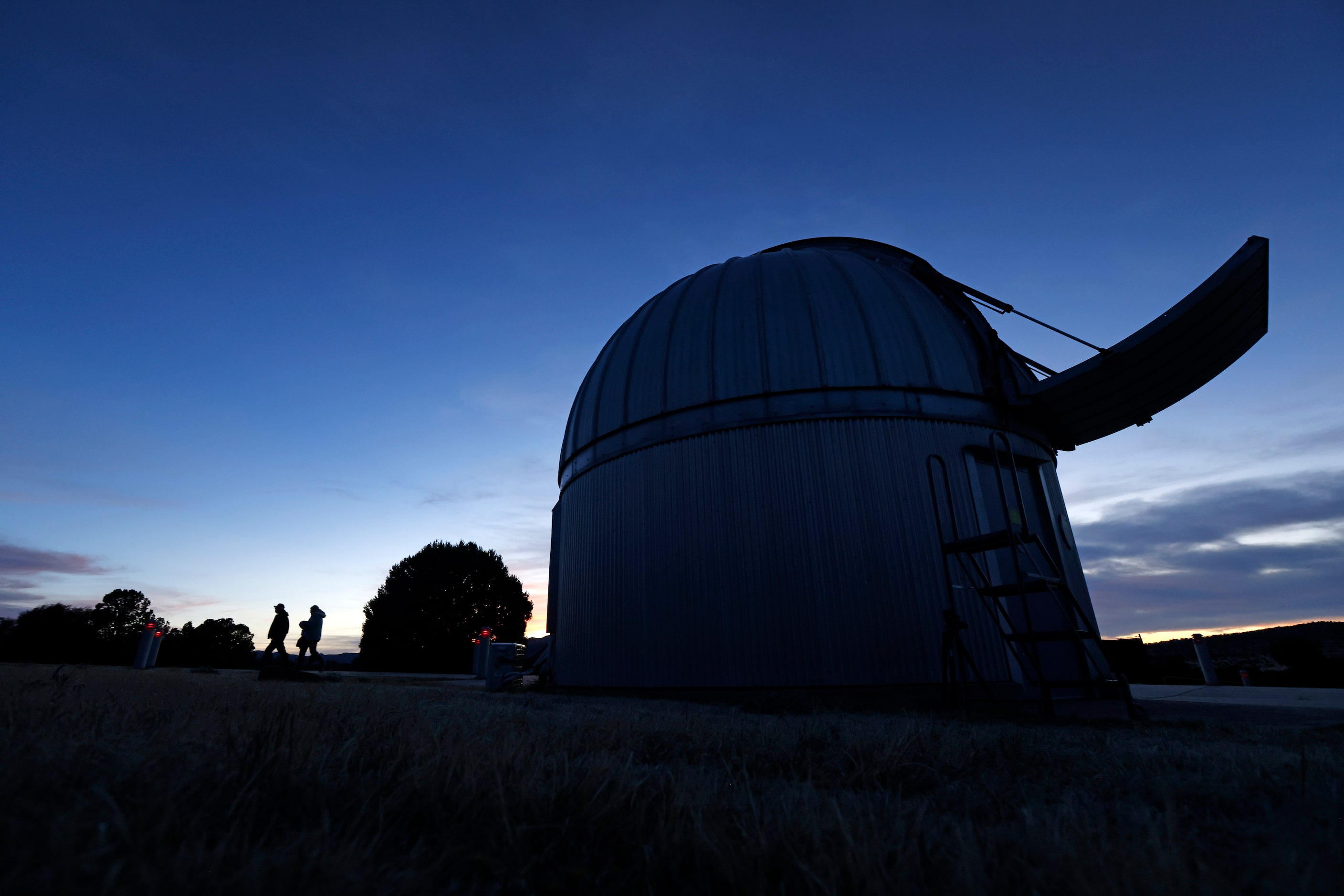 Visitors walk along the red-lighted walkway past a telescope housing at the University of...