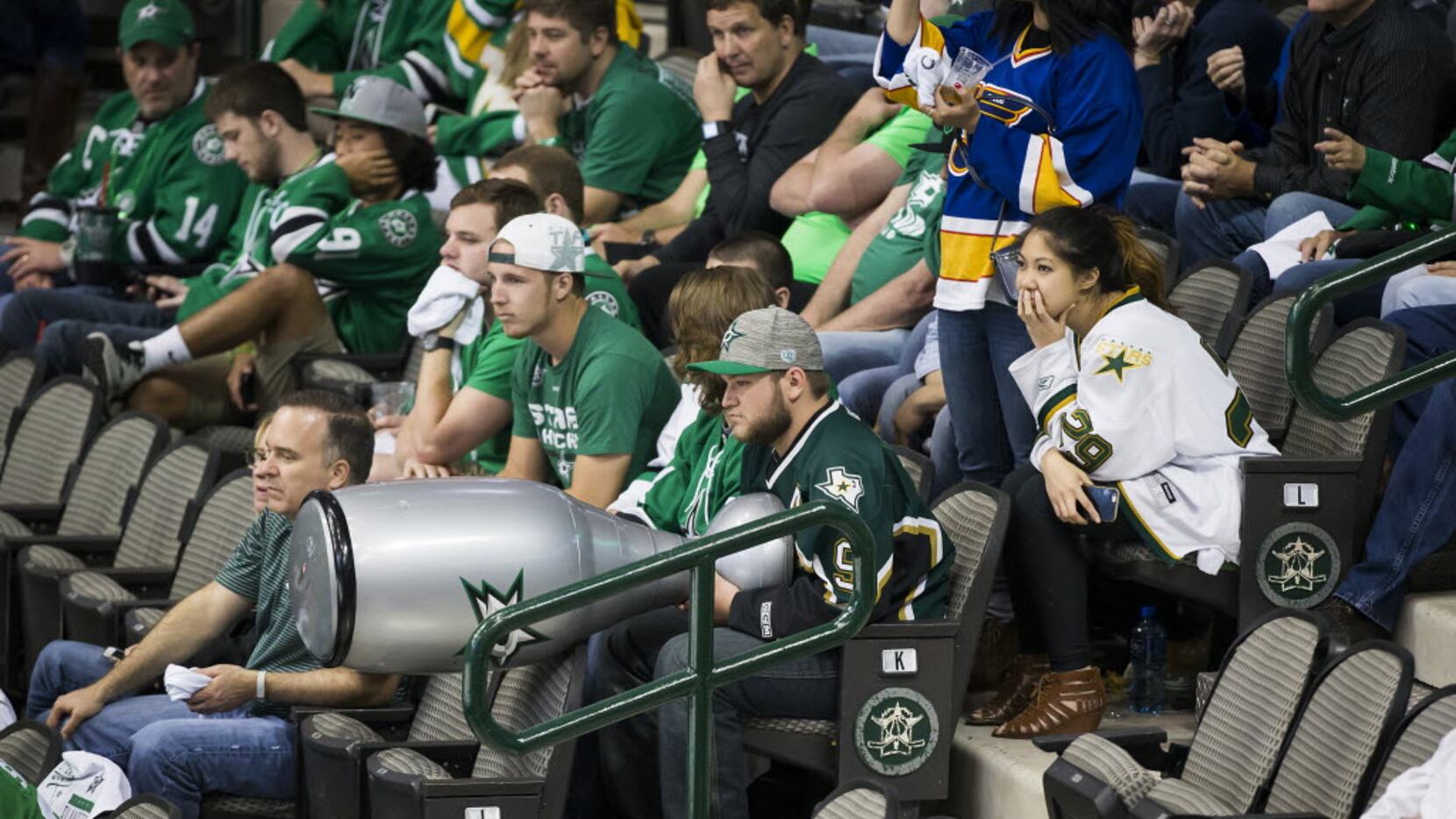 A Dallas Stars fan holds a likeness of the Stanley Cup trophy as he watches during the third...