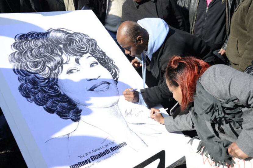 Fans signed a poster showing a picture of Whitney Houston near a funeral service for the...
