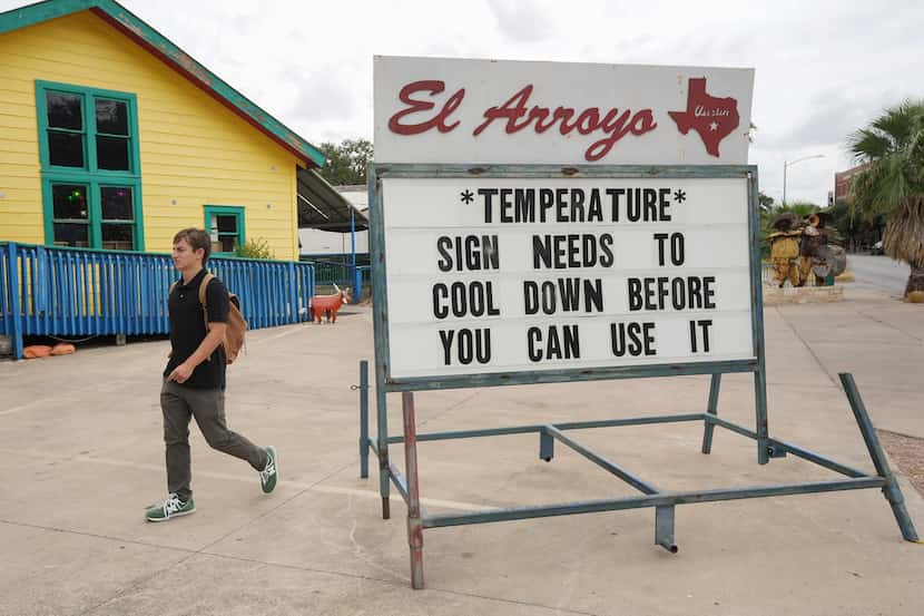 Thomas Slocombe walks past a sign that comments on the hot weather at El Arroyo Mexican...