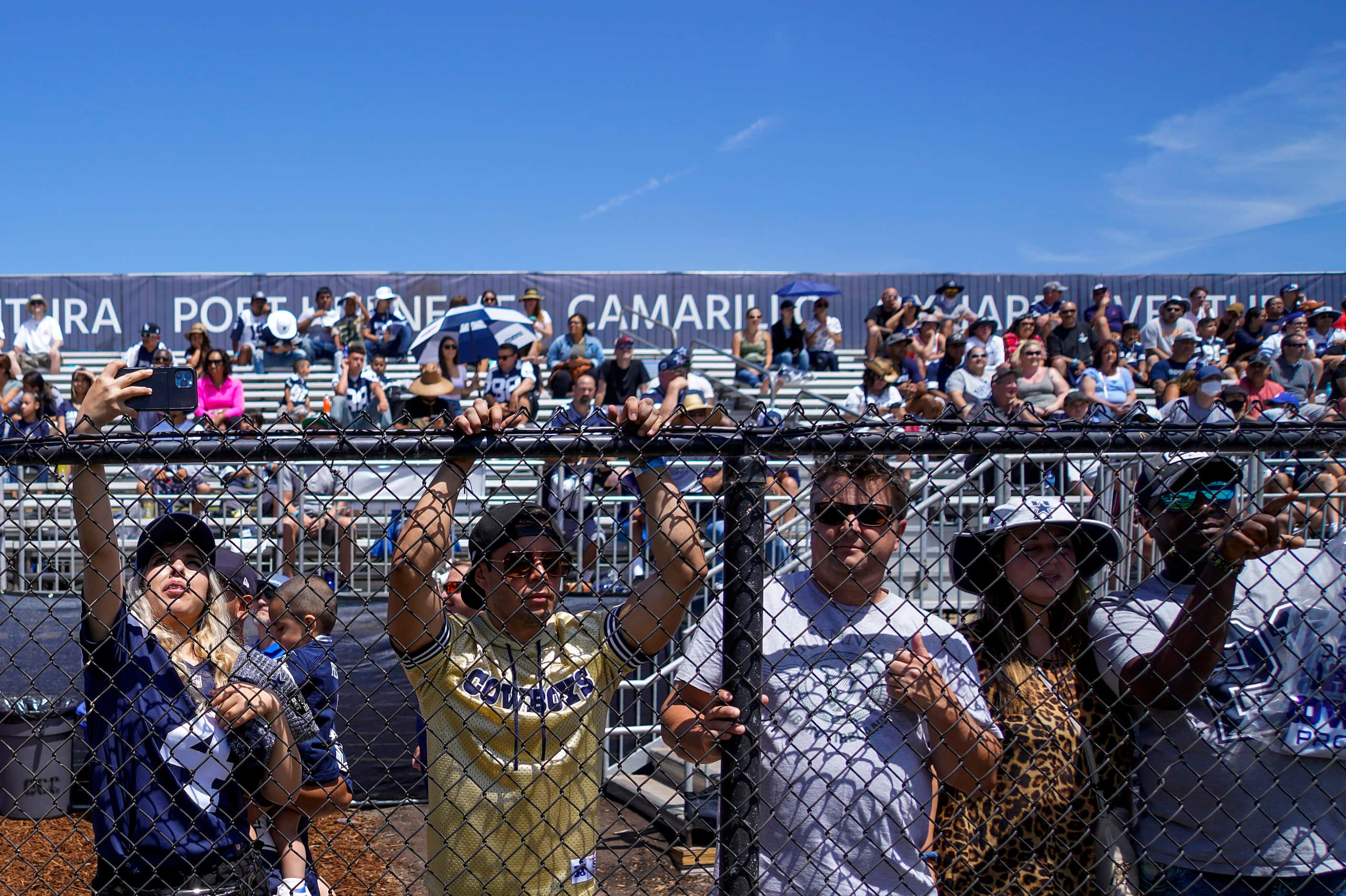Fans press against a fence to watch the Dallas Cowboys the first practice of training camp...