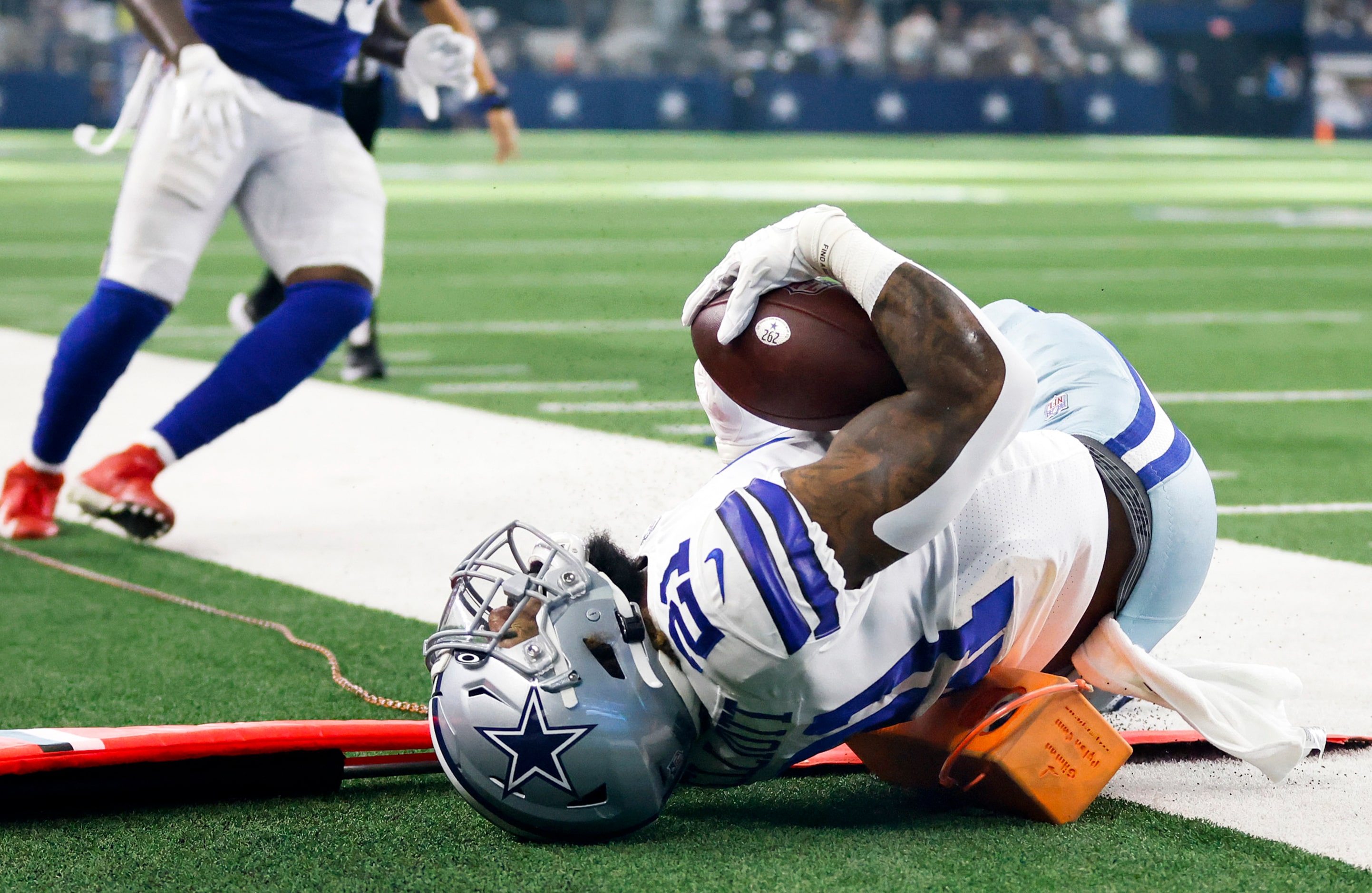 Dallas Cowboys running back Ezekiel Elliott (21) lands on a television camera pylon as he...