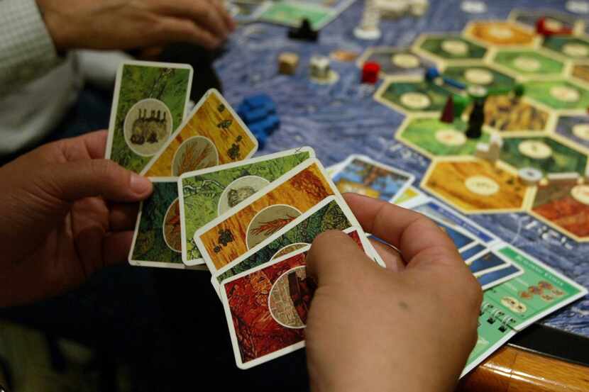 John Baxter, 34, of Dallas looks over his cards in the game 'Settlers of Catan'. while...