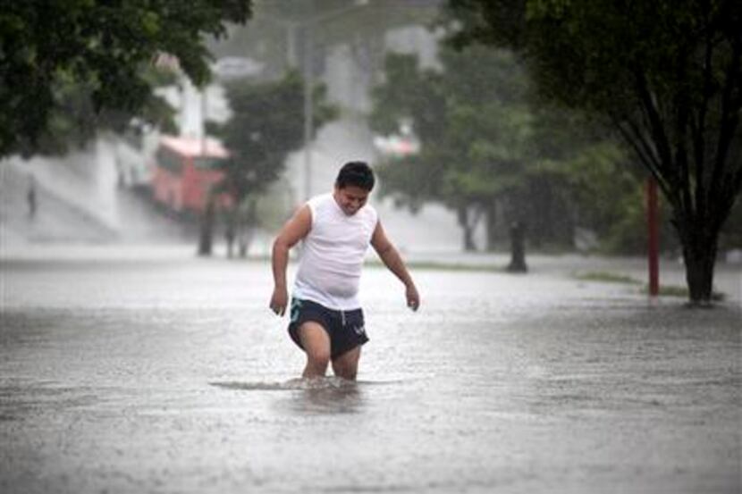 A man walks through a flooded street during heavy rains caused by Tropical Storm Ingrid in...