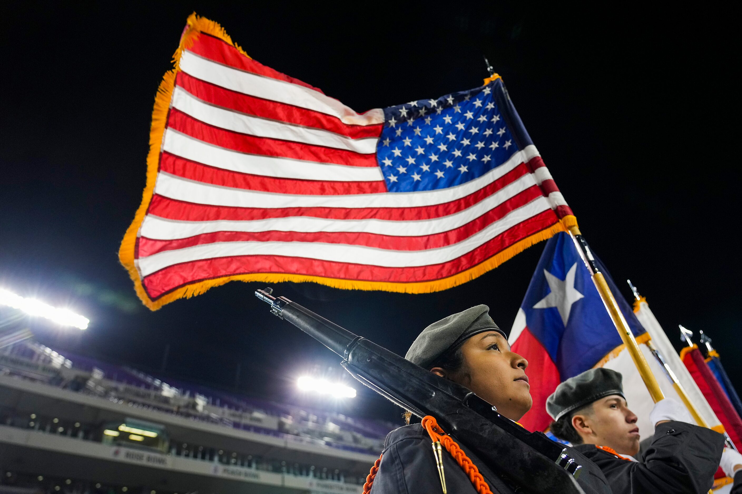 A stiff wind blows the flags as the color guard stands on the field before the Armed Forces...