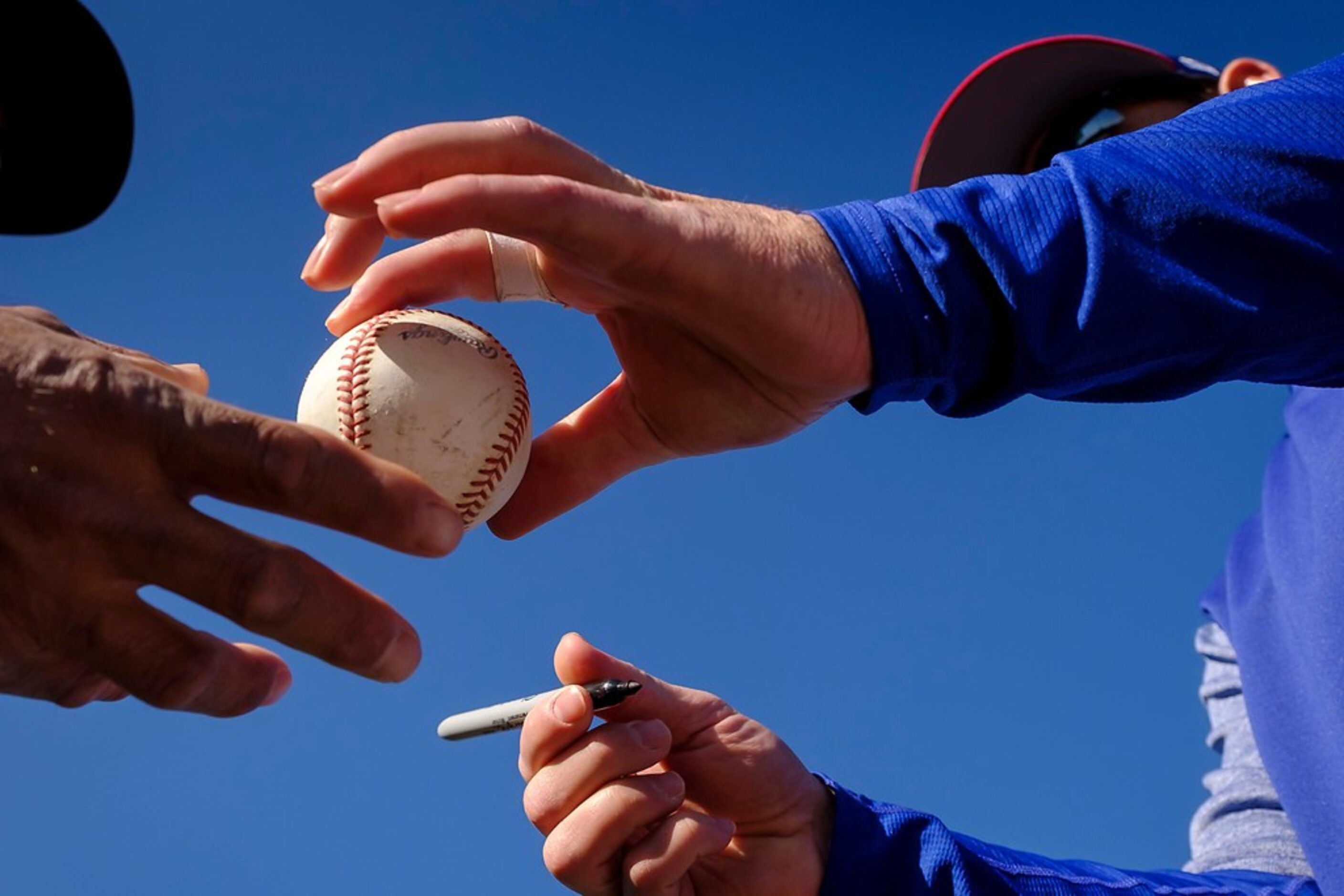 Texas Rangers catcher Jeff Mathis autographs a ball for a fan during a spring training...