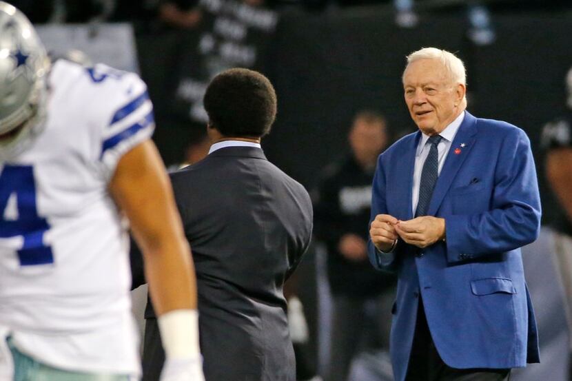 Dallas Cowboys owner Jerry Jones (right) is pictured on the field with Cowboys quarterback...