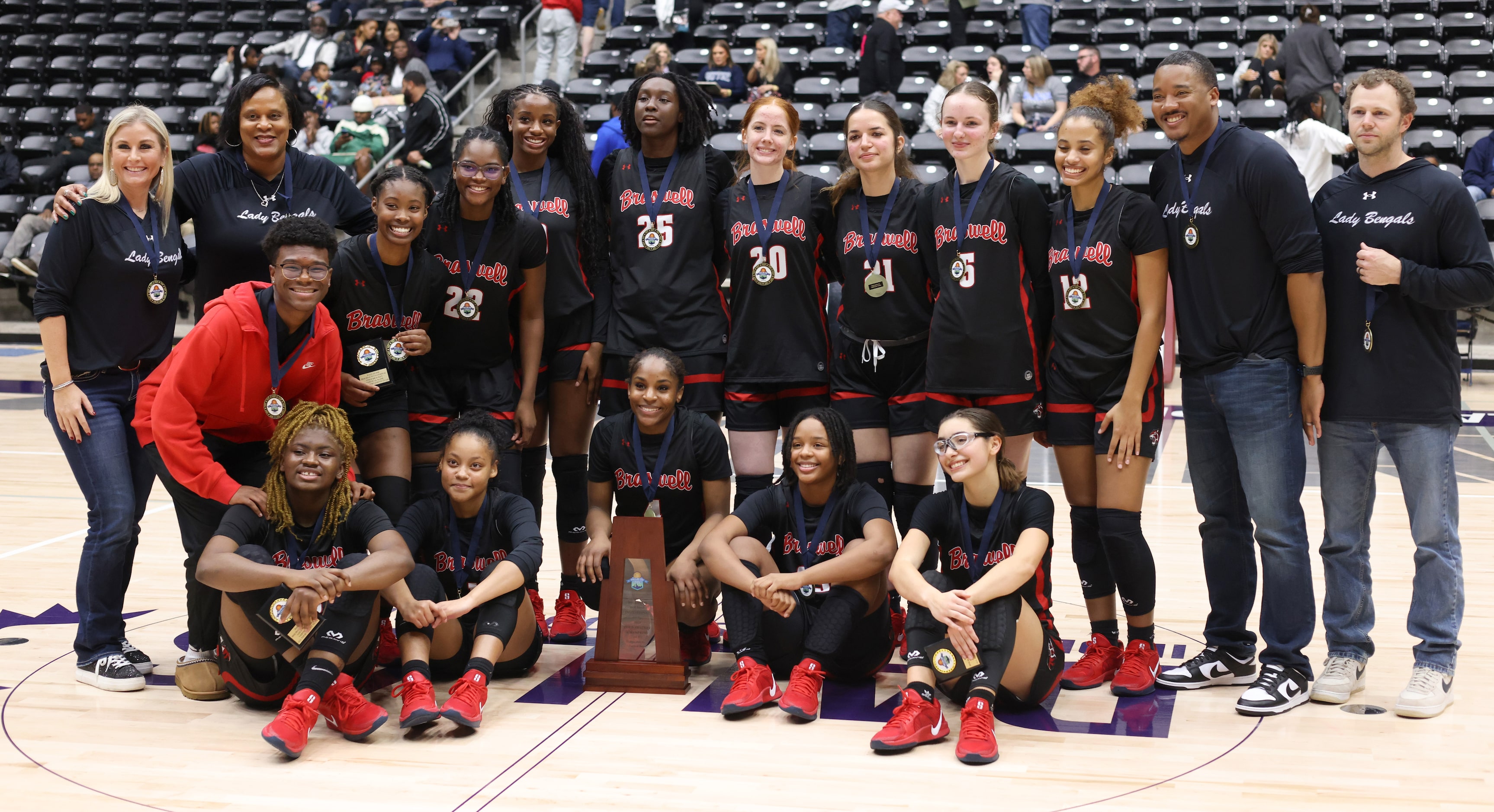 Denton Braswell players and coaches pose with their championship trophy following their...