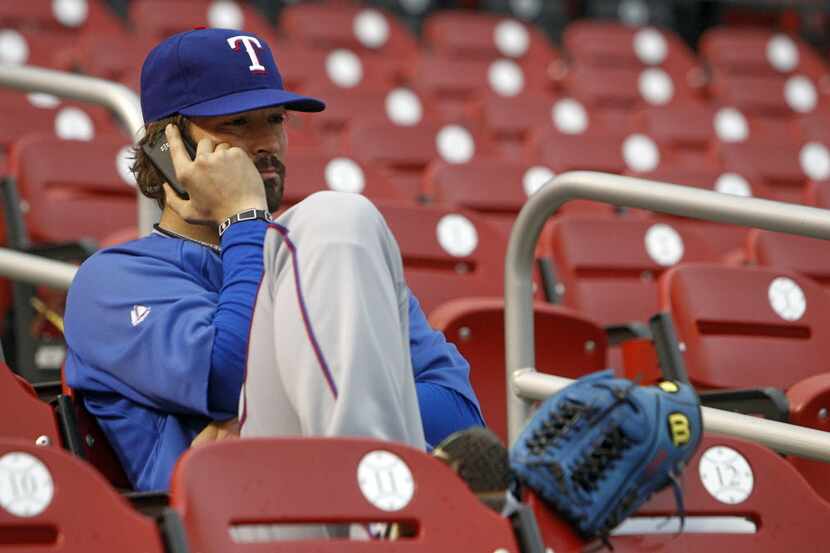 Texas Rangers starting pitcher C.J. Wilson talks on the phone before a workout on the field...
