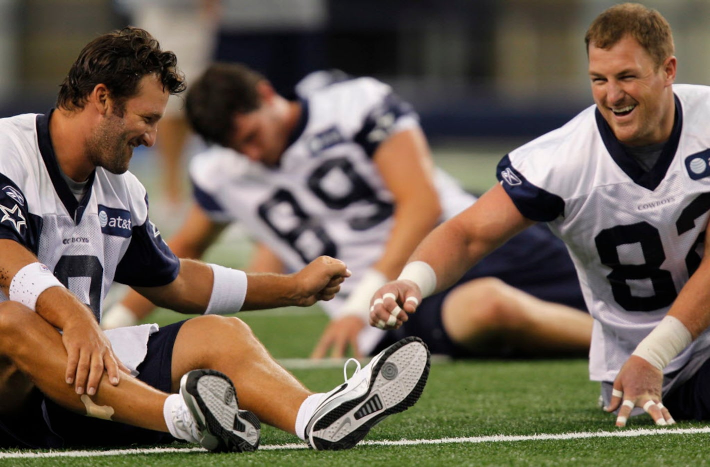 Tony Romo and Jason Witten share a laugh as they stretch out as the Dallas Cowboys hold a...