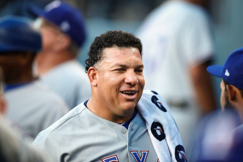 Texas Rangers starting pitcher Bartolo Colon smiles in the dugout before the team's baseball...