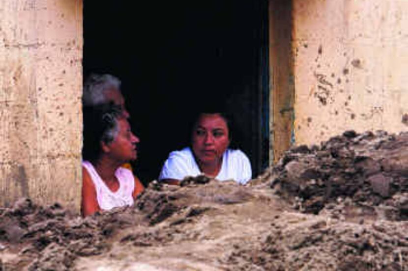 Residents discussed their situation Tuesday at a home door half covered by mud in Amatitlan,...