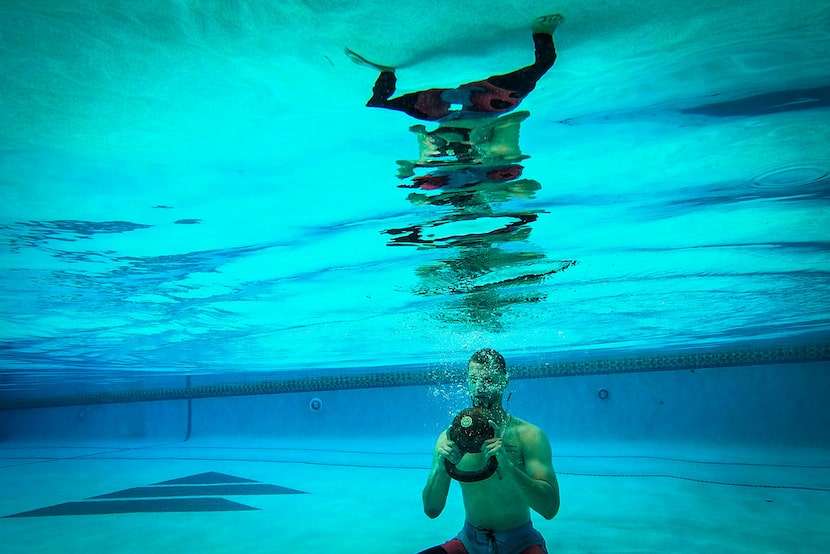 Texas Rangers pitcher Alex Claudio does squats underwater while holding a kettlebell during...