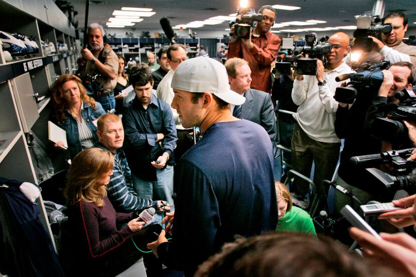 Dallas Cowboys quarterback Tony Romo, center with cap on, looks for something in  his locker...