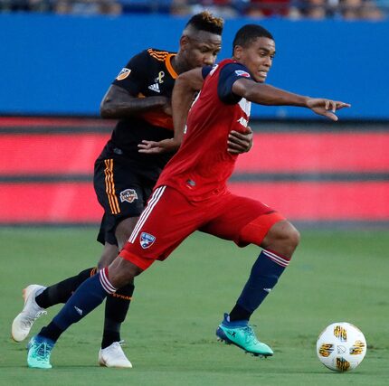 FC Dallas defender Reggie Cannon (2) is held by Houston Dynamo forward Romell Quioto (31)...