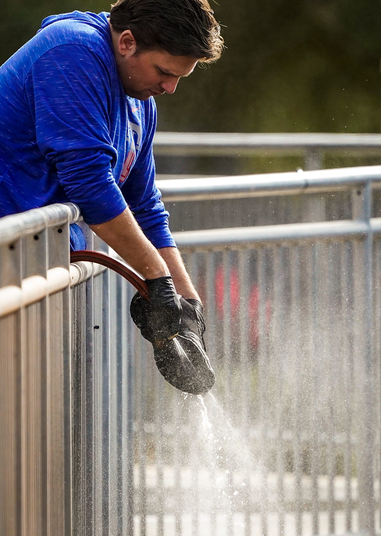 A clubhouse attended washes mud off of playerÕs cleats on the day Texas Rangers pitchers and...