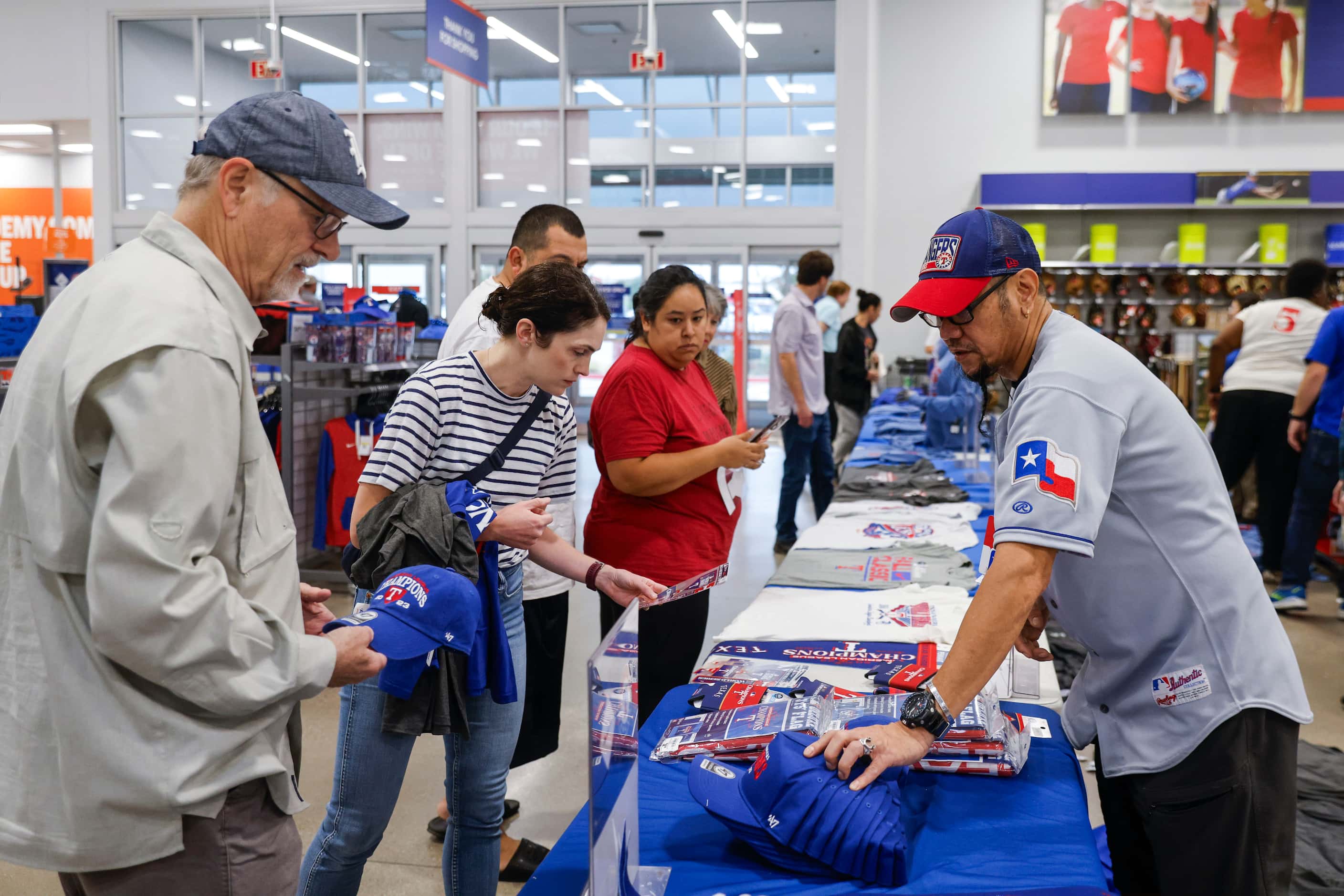 Academy Sports + Outdoors employee Allan Molina (right) helps the customers buying Texas...