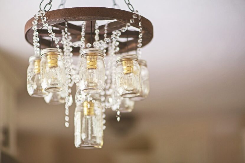 A wagon wheel and mason jar chandelier is dripping with crystals in a Junk Gypsy-designed...