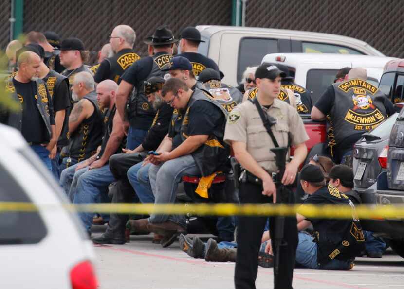 A McLennan County deputy stands guard near a group of bikers in the parking lot of a Twin...