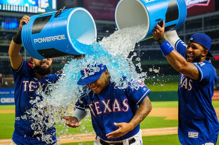 Texas Rangers left fielder Willie Calhoun is doused by second baseman Rougned Odor (12) and...