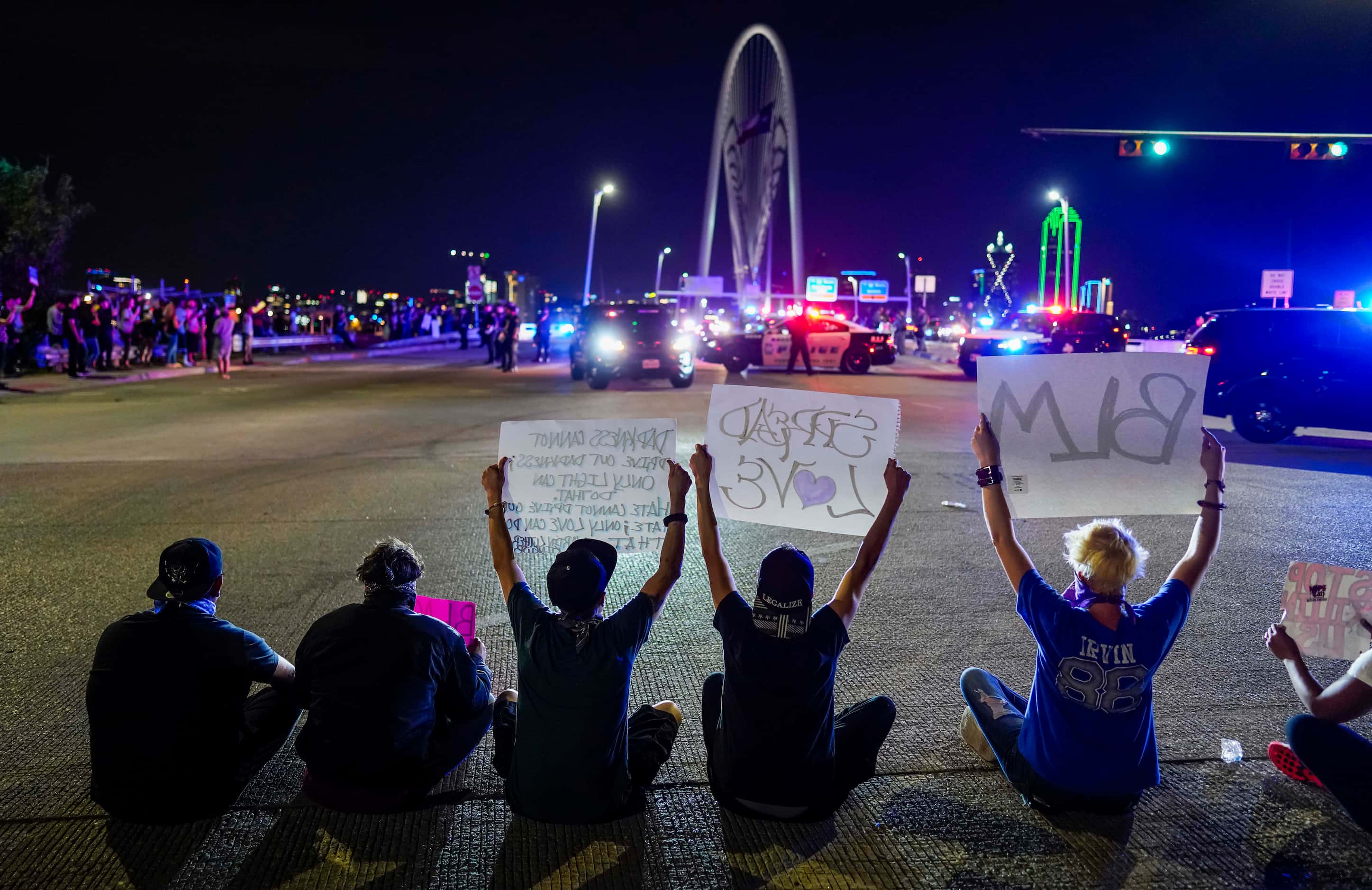 Demonstrators sit in the middle of the street in solidarity as law enforcement officers...